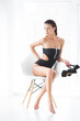 © olenachukhil - Young attractive woman holding shoes in her hands and sitting on the chair on neutral background. Sexy lady indoors. Studio portrait of beautiful model.