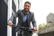 © ty - Handsome young businessman riding bicycle outdoors in the city.