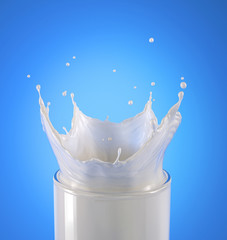 Wall Mural - Glass of milk with crown splash. Close up view, on blue background