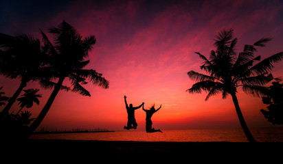 Silhouette of couple on tropical beach during sunset on background of palms and sea