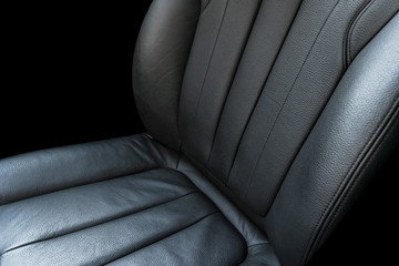 Black leather interior of the luxury modern car. Perforated Leather comfortable seats isolated on black background. Modern car interior details. Car detailing. Car inside