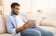 © Prostock-studio - Young african-american man reading book at home