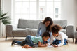 © fizkes - Loving black mom and little mixed race children drawing with colored pencils in living room, happy single african mum helping kids with creative activity at home, underfloor heating, family hobbies