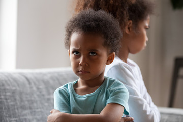 Angry african american little boy offended not talking ignoring black sister after fight, jealous kid brother sulking avoiding preschool girl, siblings bad relationships, two children conflict