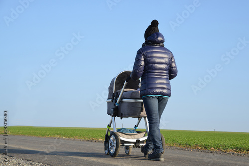 Fotografia, Obraz Walking woman with baby stroller in sunny day.