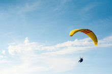 Alone Paraglider Flying In The Blue Sky Against The Background Of Clouds. Paragliding In The Sky On A Sunny Day.