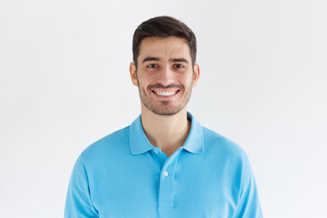 Wall Mural - Portrait of young european caucasian man isolated on gray background, standing in blue polo shirt, smiling and  looking at camera