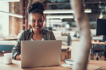 Attractive afro american girl using modern laptop at office