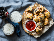 Served Appetizers Table - Minced Puff Pastry Rolls And Beer On Grey Background, Top View. Flat Lay. Sausage Rolls
