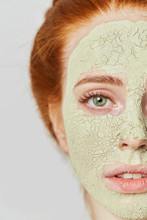 Awesome Ginger Girl With Cosmetic Green Mask On Face. Close Up Photo. Beauty Concept
