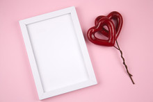 Empty White Wooden Frame And Red Heart On A Pastel Pink Background