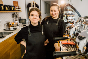 Two female baristas preparing coffee at coffee-shop. Team work and coworkers concept.