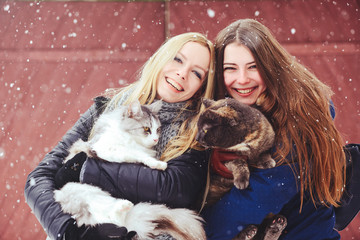 two beautiful girls with big cats in the winter outside, animal protection, fun in nature