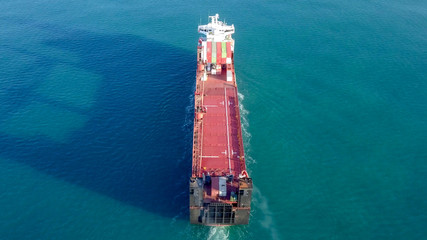 Large Cargo and RoRo (Roll On-Off) ship at sea, loaded with a small amount of shipping containers and two large cranes - Aerial image following the ship.