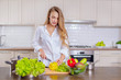 © fotoplaton - Beautiful girl in a white shirt prepares vegetables in the kitchen