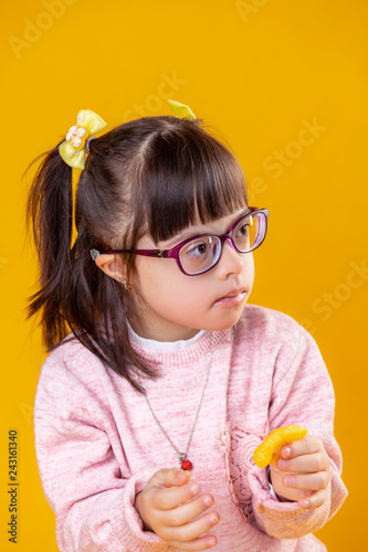 Fotografia, Obraz Dark-haired girl with down syndrome carrying orange chips