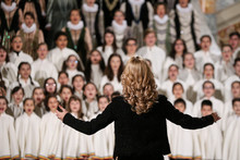 Back Of A Woman Conducting A Choir Of Children