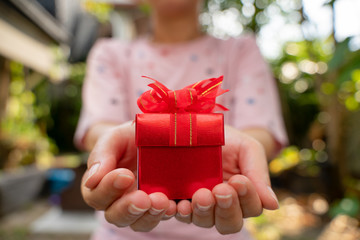 Red gift box in hand for giving in holidays. Give Valentine's Day gift box.