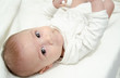 © Starmarpro - Cute tree months old baby boy dressed in white body looking at the camera while laying on the baby changer