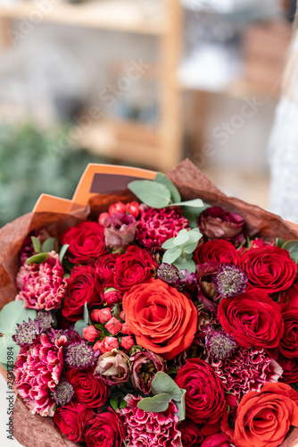 beautiful fresh cut bouquet of mixed flowers in woman hand. the work of the florist at a flower shop. Bright juicy red colors © malkovkosta