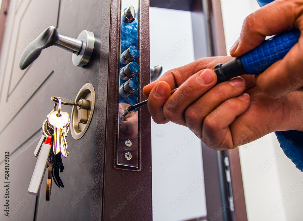 Handyman repairs the door lock - obrazy, fototapety, plakaty 