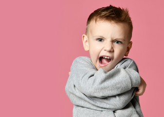 Wall Mural - Baby boy kid covering hug himself with hands screaming laughing  over pink 