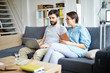 © pressmaster - Young spouses sitting on sofa and looking through online hot tour offers while choosing suitable one