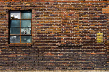 Old brick wall with brick filled window.