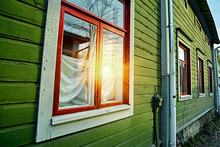 Window At The Wooden Green Wall Of Traditional Old Vintage Rural Cottage House In Finland Countryside Village. Sun Flare Reflection In The Window