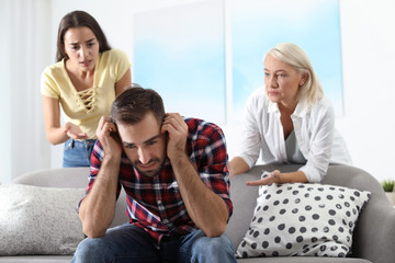 Wall Mural - Young man having argument with wife and mother-in-law at home. Family quarrel