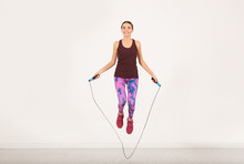 Full Length Portrait Of Young Sportive Woman Training With Jump Rope In Light Room