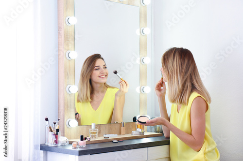 Cuadros en Lienzo Woman applying makeup near mirror with light bulbs in dressing room