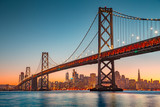 Fototapeta Mosty linowy / wiszący - San Francisco skyline with Oakland Bay Bridge at sunset, California, USA