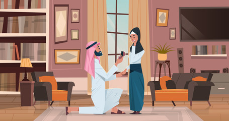 arab man kneeling holding engagement ring proposing arabic woman marry him couple in love wedding marriage offer happy valentines day concept living room interior