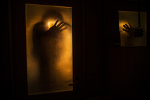 Horror Silhouette Of Woman In Window. Scary Halloween Concept Blurred Silhouette Of Witch In Bathroom