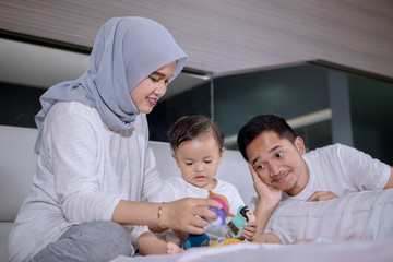 Wall Mural - Parents playing with their baby girl in the bedroom