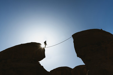 a man balancing walking on rope over precipice. business, risk taking, challenge,bravery, and concen