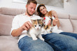 © ruslanshug - beautiful young couple man and female sitting on couch indoors with many kittens
