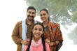 © IndiaPix - Portrait of a smiling village man standing with his wife and daughter posing for a family photo.