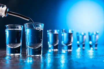 Vodka poured into a glass lit with blue backlight.