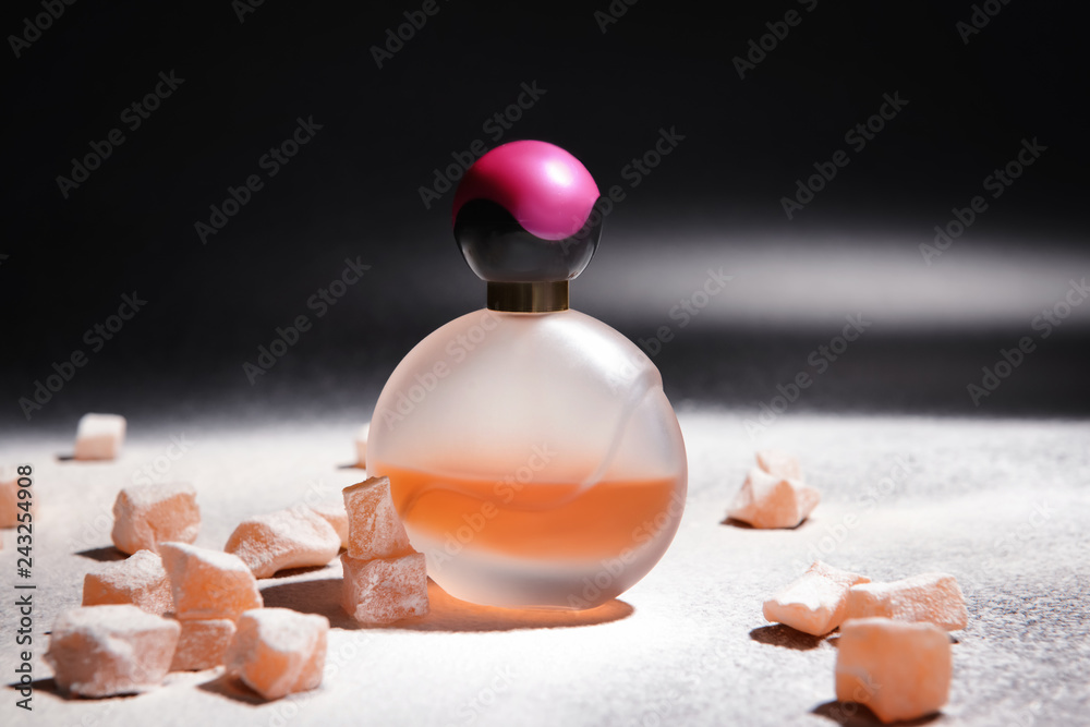 Bottle of perfume and rahat lakoum on table against dark background