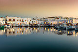 Fototapeta  - Abend über dem idyllischen Fischerdorf Naousa mit den zahlreichen Tavernen und Restaurants direkt am Hafen auf Paros, Kykladen, Griechenland 