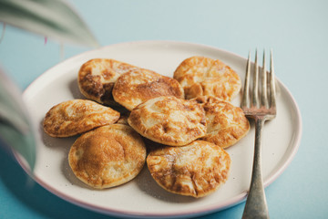 Wall Mural - Dutch mini pancakes called poffertjes, sprinkled with powdered sugar. Healthy food concept with copy space. Toned photo.