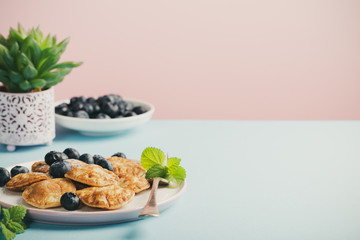 Wall Mural - Dutch mini pancakes called poffertjes with blueberries, sprinkled with powdered sugar. Healthy food concept with copy space. Toned.