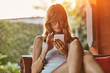 © astrosystem - Cute woman using smartphone on a porch sofa.
