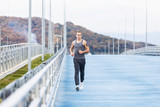 Fototapeta Młodzieżowe - Nice tall young male runner runs through a scenic nature during a morning jog. Concept of weight loss and cardio. Place for your advertising content