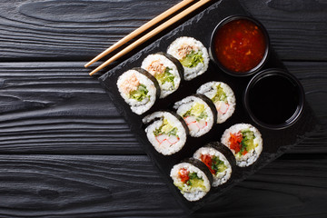 Wall Mural - Freshly made rolls with various fillings served with soy and chili sauces close-up on a slate board. horizontal top view