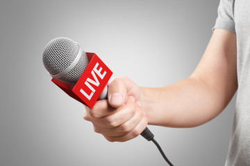 Wall Mural - Male hand holding a microphone, isolated on grey background