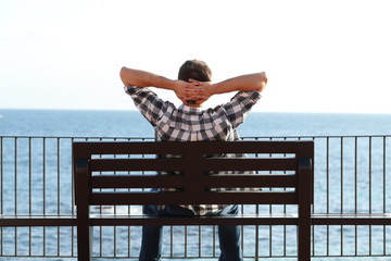 Man relaxing on the beach sitting on a bench