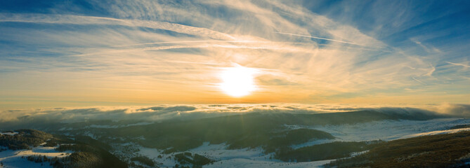 Aerial view of a gold sunset over winter snow. Panorama.